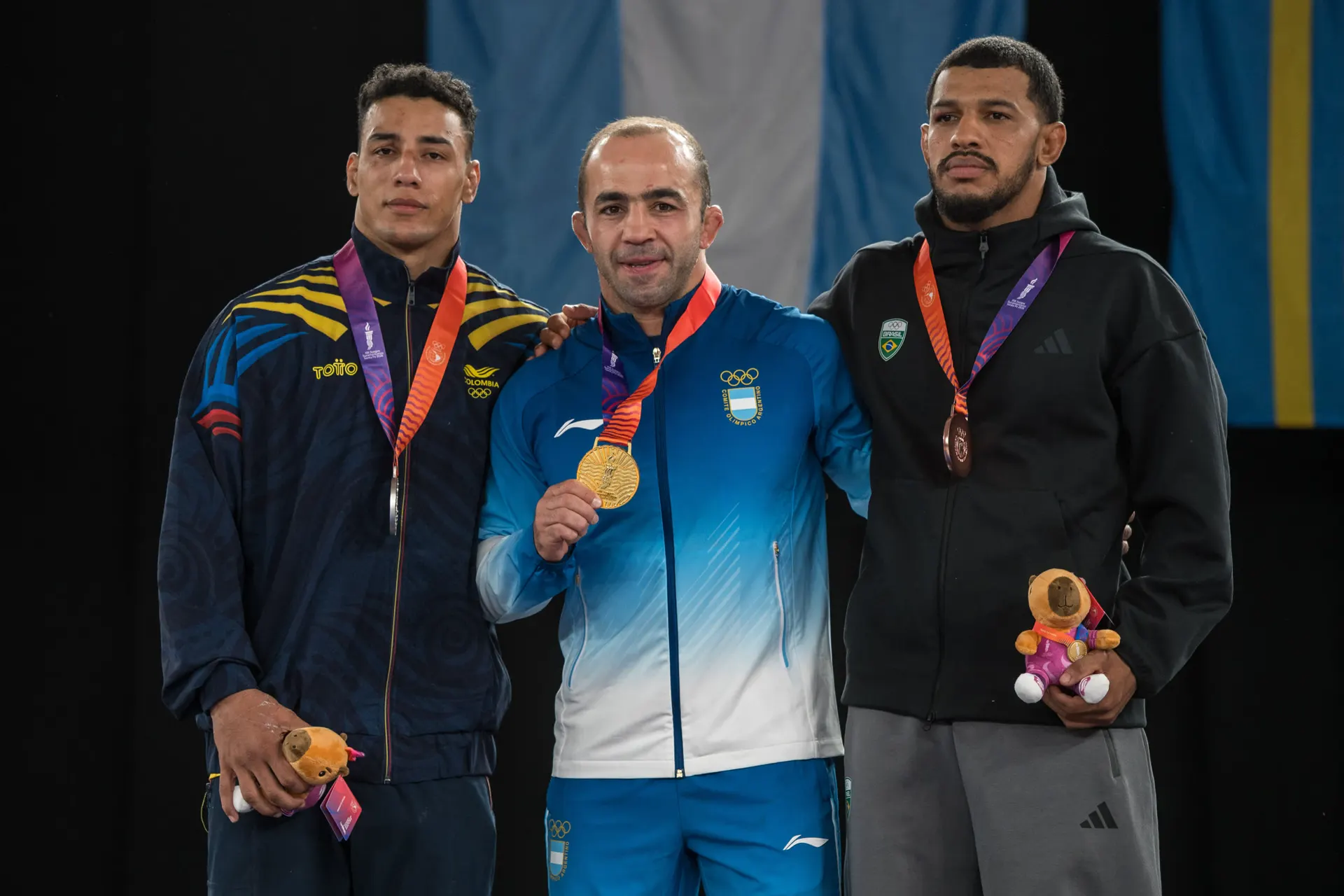Arsen Julfalakyan en el centro del podio con la medalla de oro de lucha grecorromana, Santa Fe 2026.